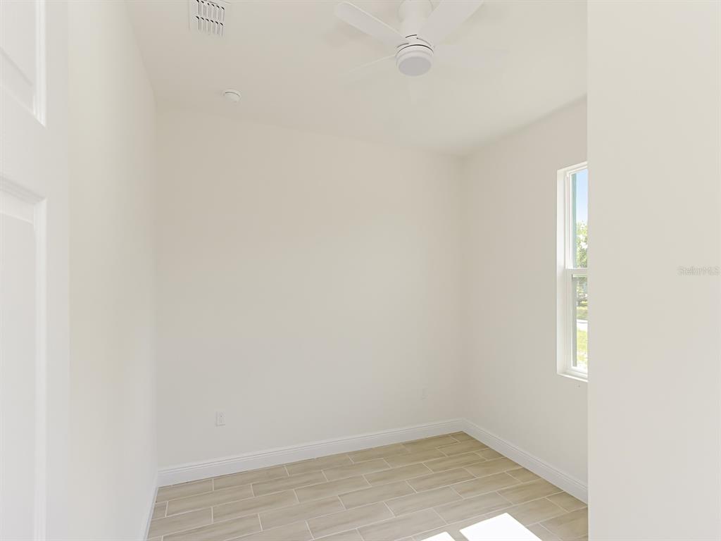 A small, empty room features light-colored tile flooring, white walls, and a ceiling fan — 1216 S POMEGRANITE AVENUE, SANFORD, FL
