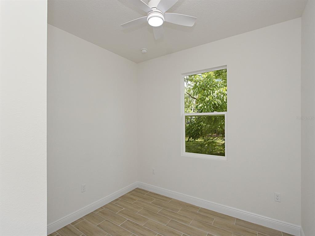 An empty room with white walls, a ceiling fan, and light-colored wood-look tile flooring — 1216 S POMEGRANITE AVENUE, SANFORD, FL
