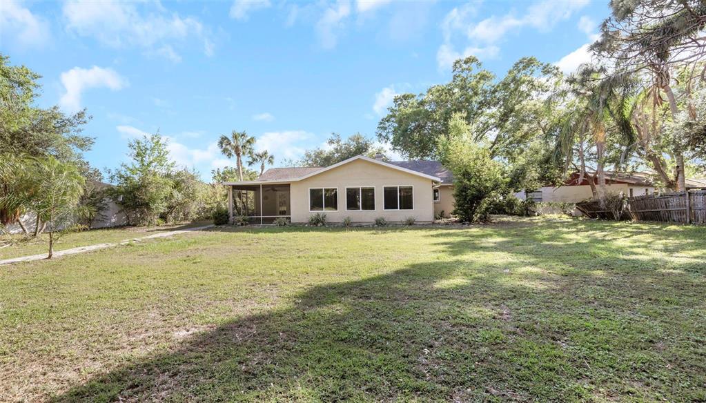 The exterior of a single-story house features a screened porch and a large grassy yard — 4101 WINDTREE DRIVE, TAMPA, FL