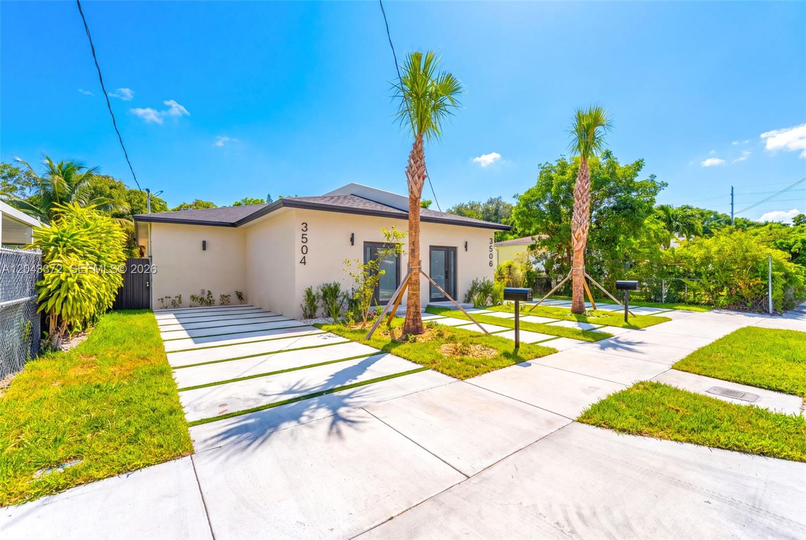 A modern, single-story duplex with a light-colored exterior, palm trees, and concrete paver driveways — 3506 NW 9th Ave, Miami FL 33127, MIAMI, FL