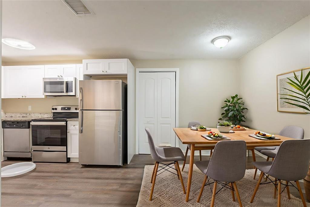 A kitchen with stainless steel appliances and white cabinets adjacent to a dining area — 2115 E ELLICOTT STREET, TAMPA, FL