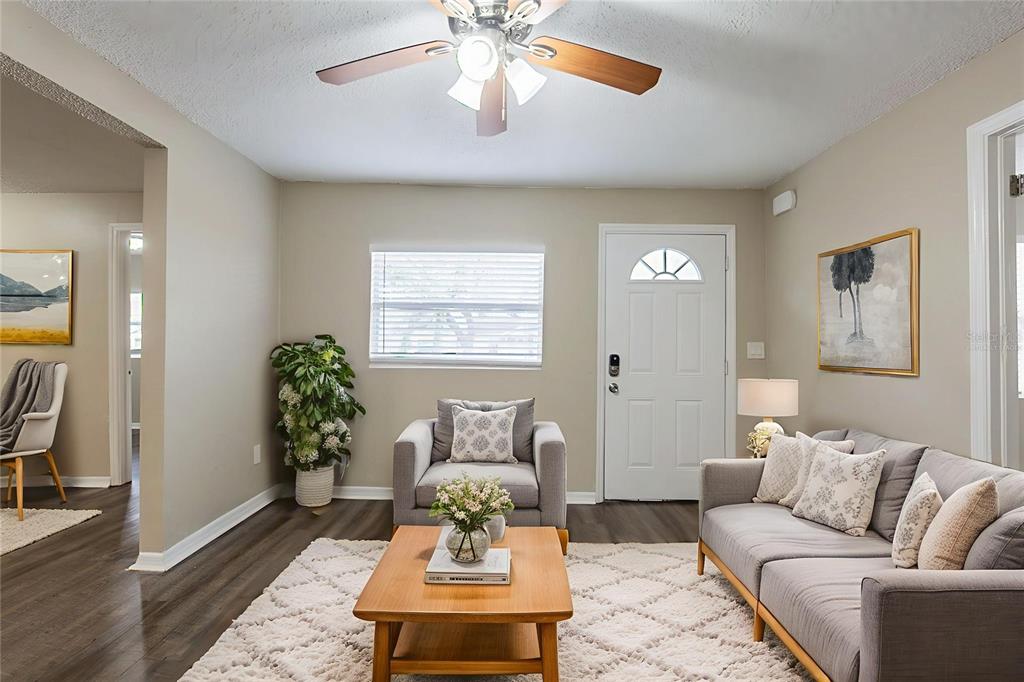 A living room features gray furniture, a wooden coffee table, and a white ceiling fan — 2115 E ELLICOTT STREET, TAMPA, FL