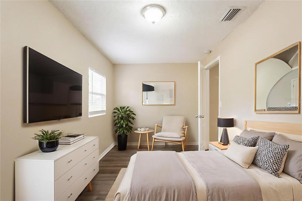 A bedroom features a bed, a white dresser with a television, and a small seating area — 2115 E ELLICOTT STREET, TAMPA, FL