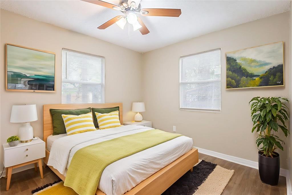 A bedroom features a wooden bed frame, two windows, a ceiling fan, and two paintings — 2115 E ELLICOTT STREET, TAMPA, FL