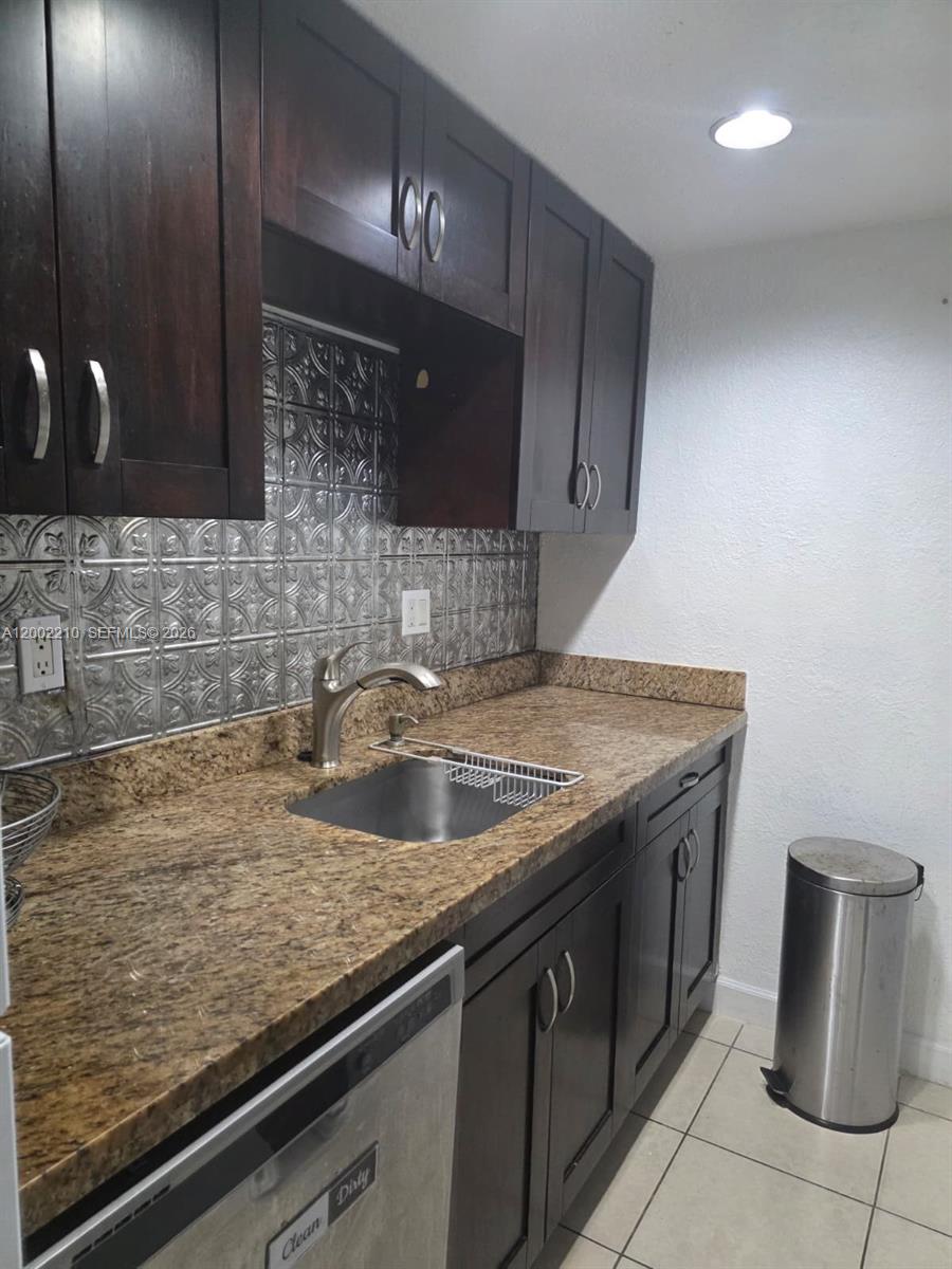 A kitchen features dark wood cabinets, granite countertops, and a metallic patterned tile backsplash — 5055 NW 7th St # 602, Miami FL 33126, MIAMI, FL