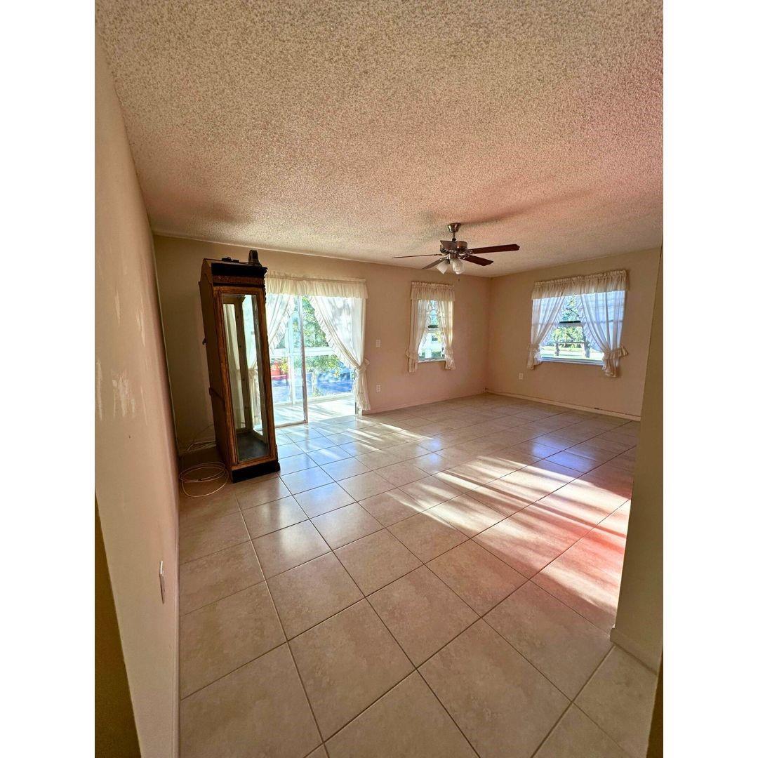 A living room with light-colored tile flooring, a ceiling fan, and sliding glass patio doors — 5190 E Sabal Palm Boulevard # 201, Tamarac FL 33319, TAMARAC, FL