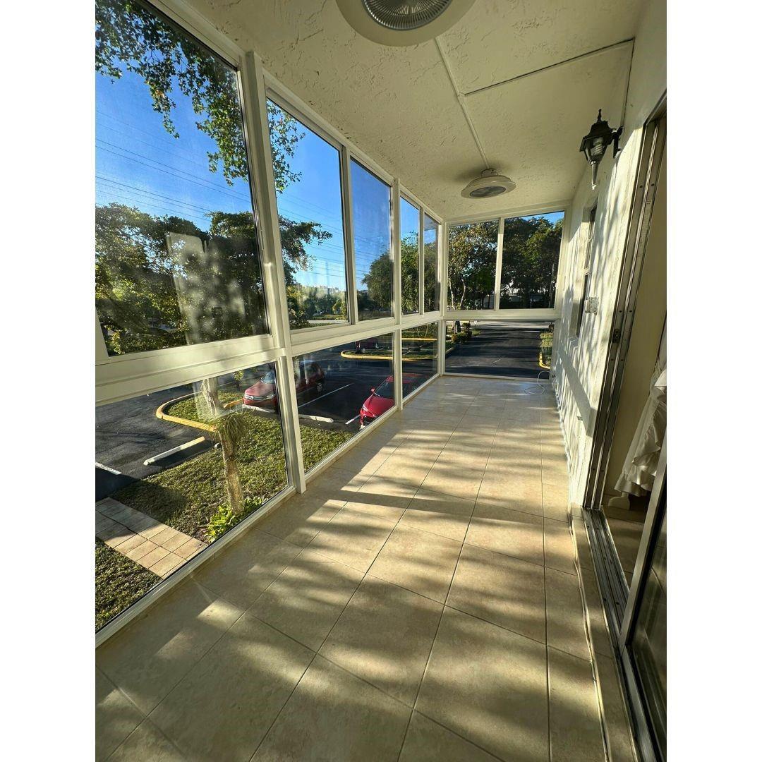 A sunroom with tiled flooring, large glass windows, and a view of a parking lot — 5190 E Sabal Palm Boulevard # 201, Tamarac FL 33319, TAMARAC, FL