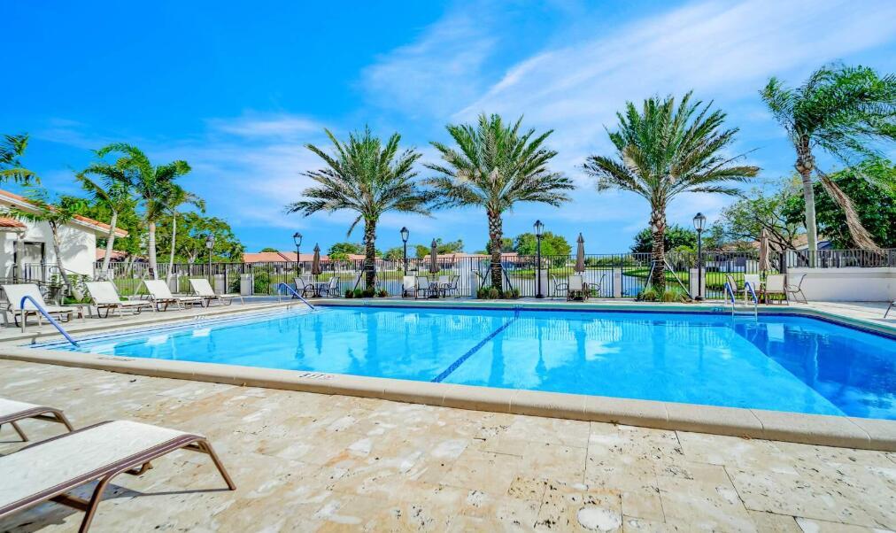 A swimming pool with lounge chairs on a stone patio surrounded by palm trees — 20020 Rima Circle, Boca Raton FL 33434, BOCA RATON, FL