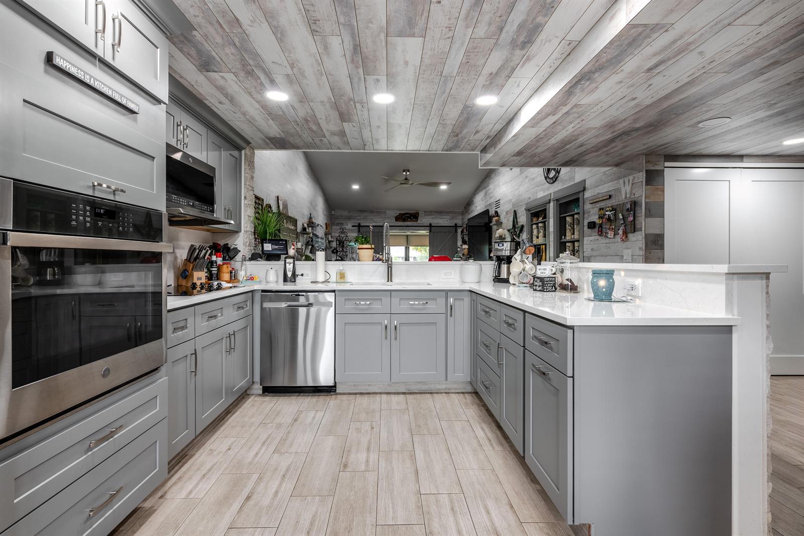 A kitchen features gray cabinets, white countertops, stainless steel appliances, and a wood-planked ceiling — 7418 Victory Lane # 9805, Delray Beach FL 33446, DELRAY BEACH, FL