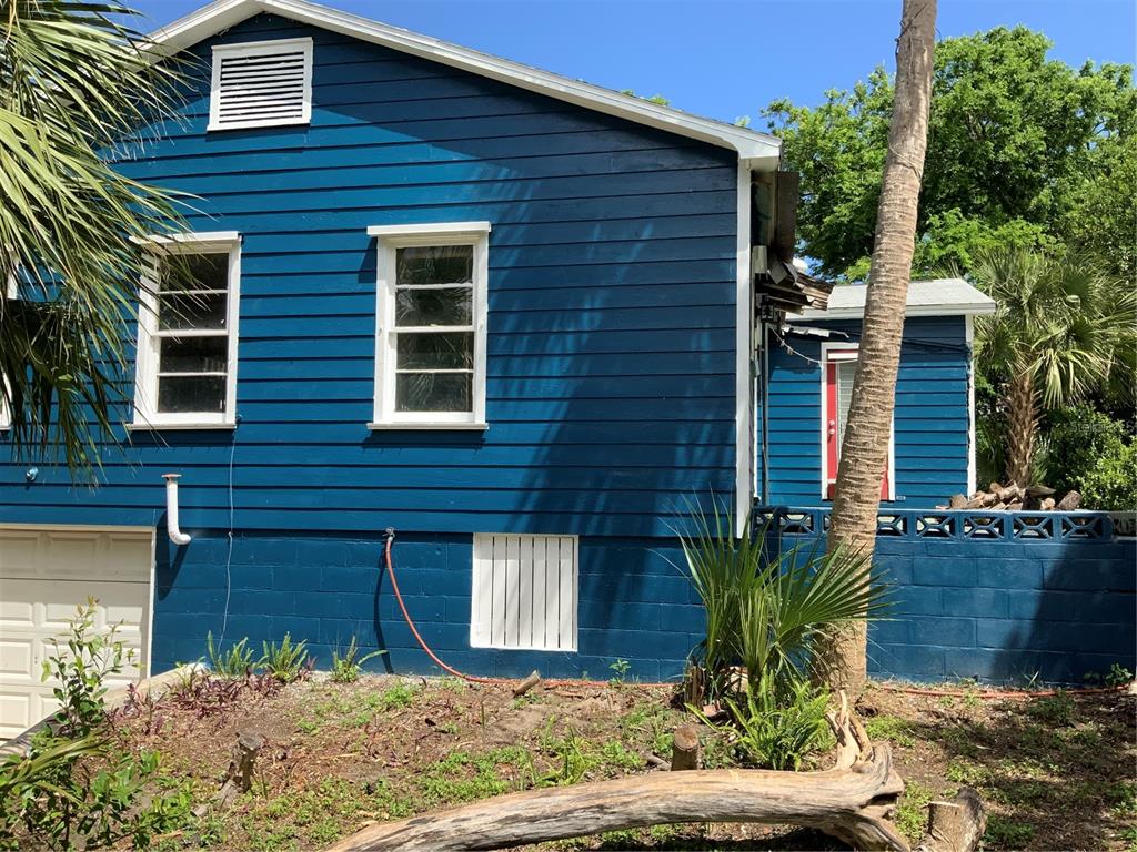A blue house exterior features white-trimmed windows, a garage door, and a concrete block foundation — 116 BRADDOCK AVENUE, DAYTONA BEACH, FL