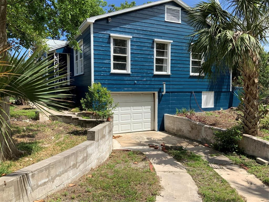 A blue, two-story house with a white garage door and a concrete retaining wall — 116 BRADDOCK AVENUE, DAYTONA BEACH, FL