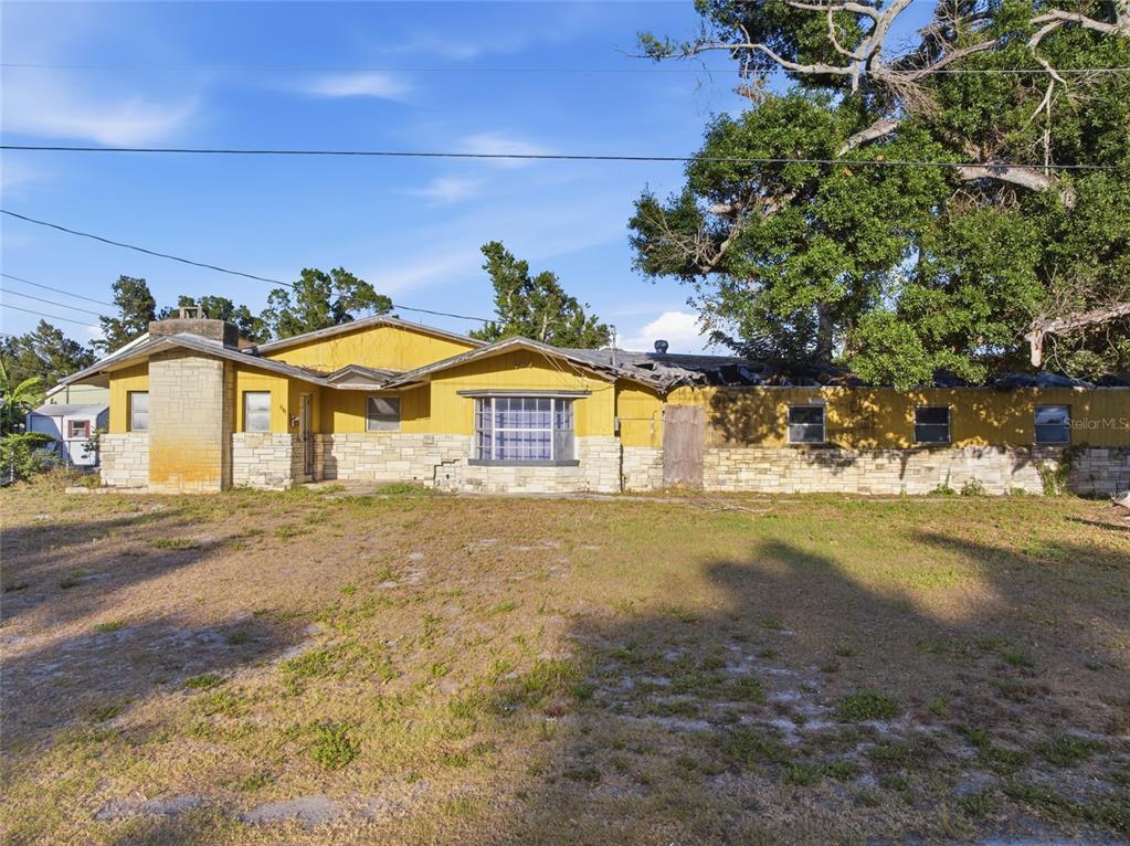 A single-story house with yellow siding, a stone base, and a damaged roof — 8181 61ST LANE N, PINELLAS PARK, FL