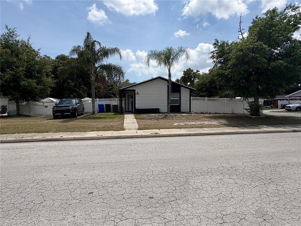 A single-story house with light siding and a dark trim sits behind a white fence — 1010 VAN LIEU STREET, KISSIMMEE, FL