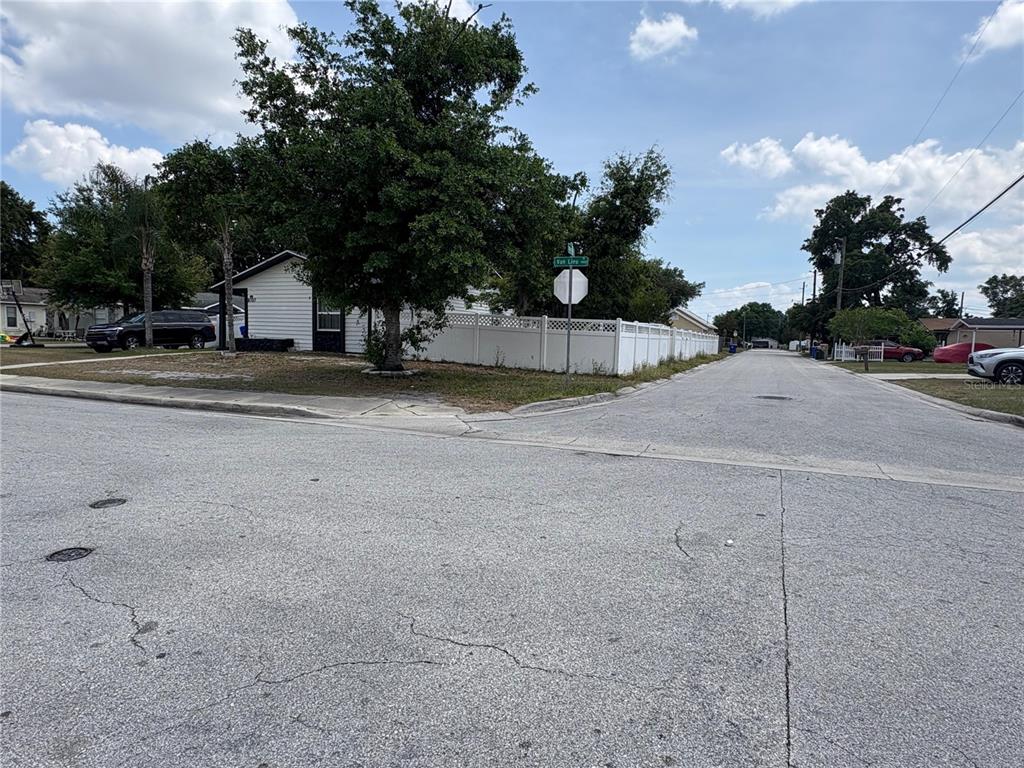A street corner view shows a white house with a fence and a stop sign — 1010 VAN LIEU STREET, KISSIMMEE, FL