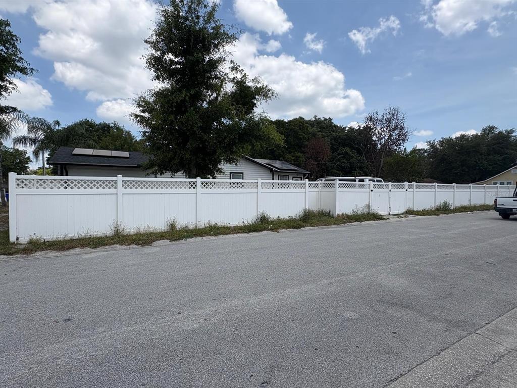 A white vinyl privacy fence with lattice top runs along the edge of a street — 1010 VAN LIEU STREET, KISSIMMEE, FL