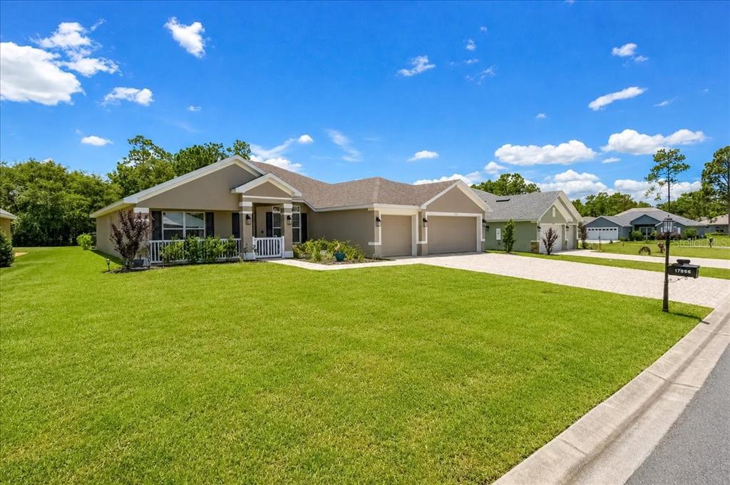 A single-story suburban house with a tan stucco exterior, a two-car garage, and a lawn — 17866 SW 68TH PLACE, DUNNELLON, FL