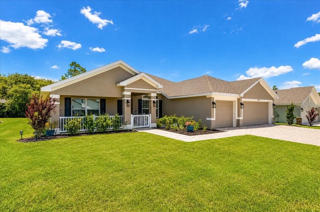 A single-story house with a tan stucco exterior, a two-car garage, and a front porch — 17866 SW 68TH PLACE, DUNNELLON, FL