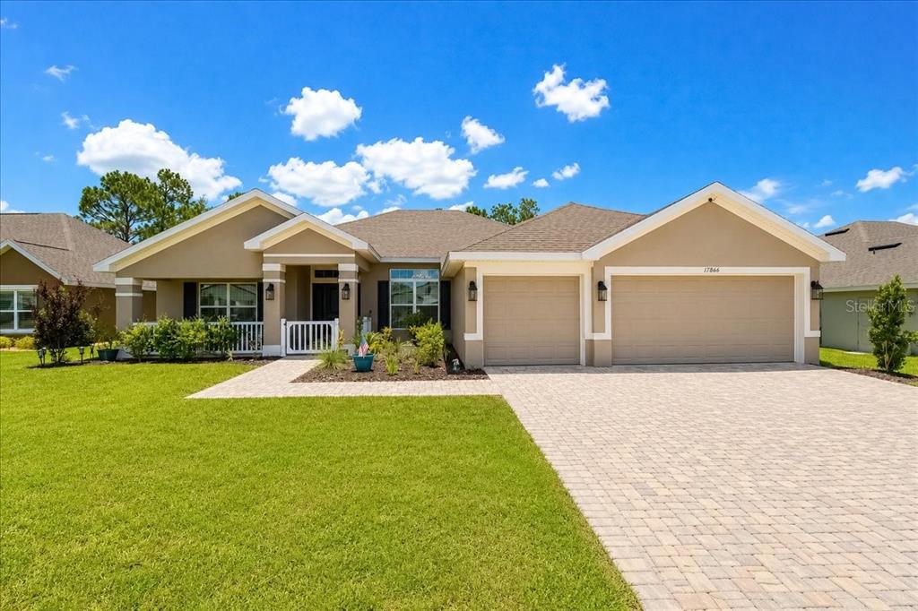 A single-story house with a beige exterior, a three-car garage, and a paved driveway — 17866 SW 68TH PLACE, DUNNELLON, FL