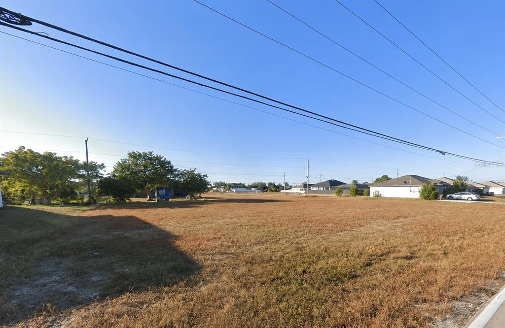 A large, flat, vacant grassy lot under a clear blue sky — 1804 KISMET PARKWAY W, CAPE CORAL, FL