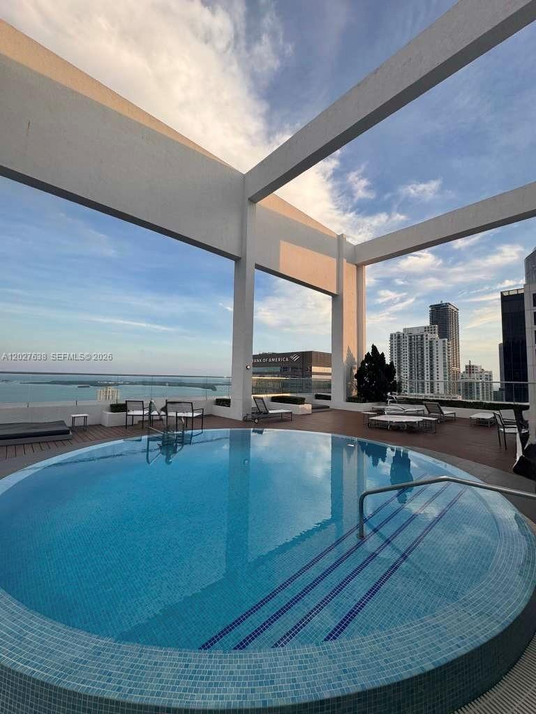 A circular rooftop swimming pool overlooks a city skyline and a body of water — 500 Brickell Ave # 3910, Miami FL 33131, MIAMI, FL