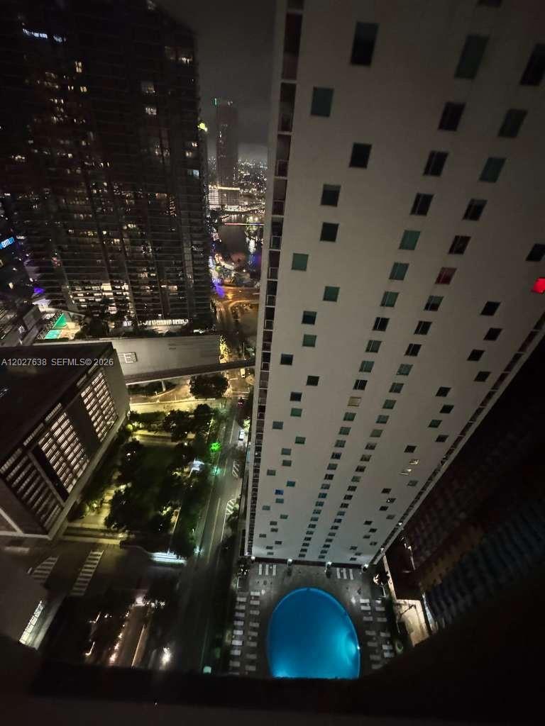 A high-angle night view shows a swimming pool, city streets, and surrounding high-rise buildings — 500 Brickell Ave # 3910, Miami FL 33131, MIAMI, FL