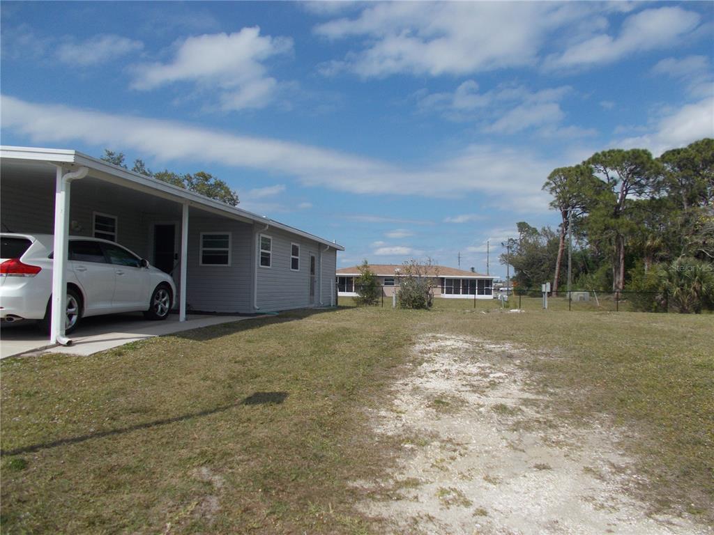 A white car is parked under a carport next to a single-story house with siding — 5552 HOLIDAY PARK BOULEVARD, NORTH PORT, FL