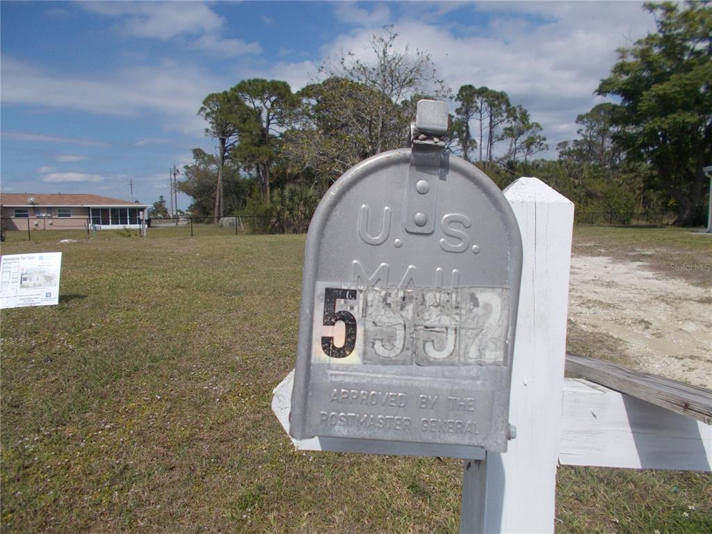 A metal mailbox with the number 5552 stands in front of a vacant grassy lot — 5552 HOLIDAY PARK BOULEVARD, NORTH PORT, FL