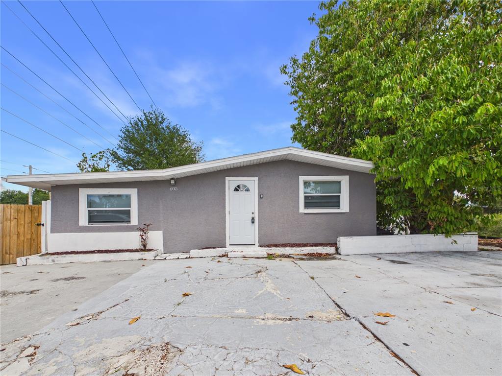 A single-story gray house with a white door and a large concrete driveway — 605 S DISSTON AVENUE, TARPON SPRINGS, FL