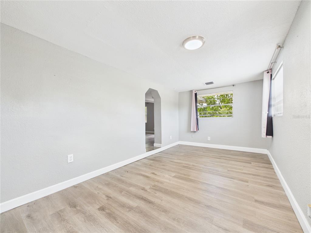 An empty room with light gray walls, wood-look flooring, and a window with curtains — 605 S DISSTON AVENUE, TARPON SPRINGS, FL