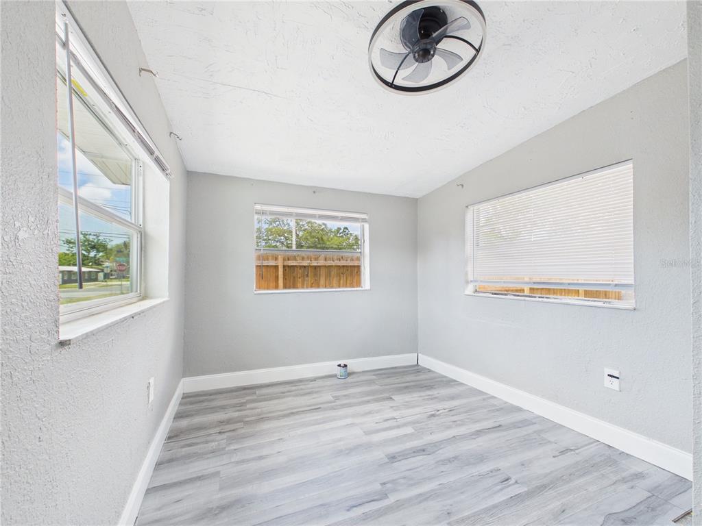 A small, empty room with light gray walls, wood-look flooring, and three windows — 605 S DISSTON AVENUE, TARPON SPRINGS, FL