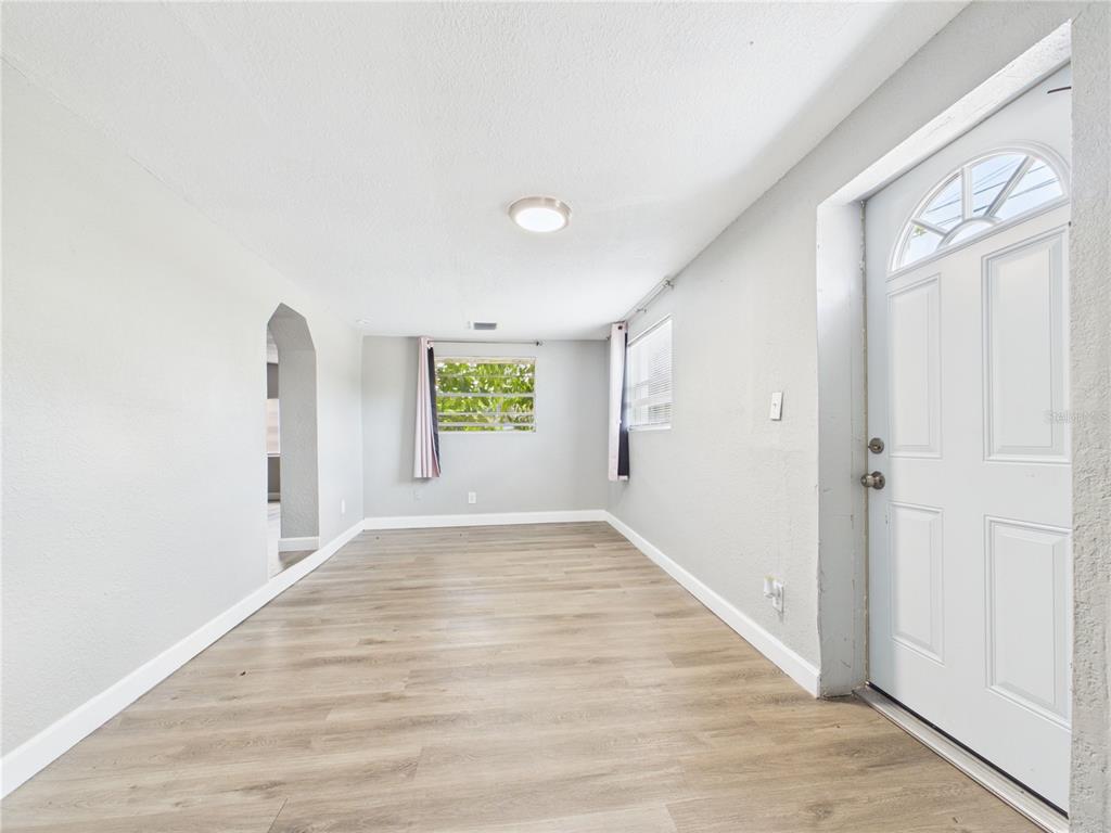 An empty room with light gray walls, wood-look flooring, a front door, and a window — 605 S DISSTON AVENUE, TARPON SPRINGS, FL