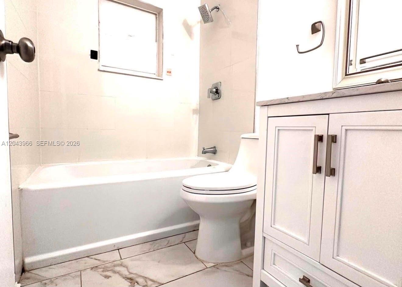 A bathroom features a white vanity, a toilet, and a bathtub with tiled walls — 709 NW Cuxhaven St, Palm Bay FL 32907, PALM BAY, FL