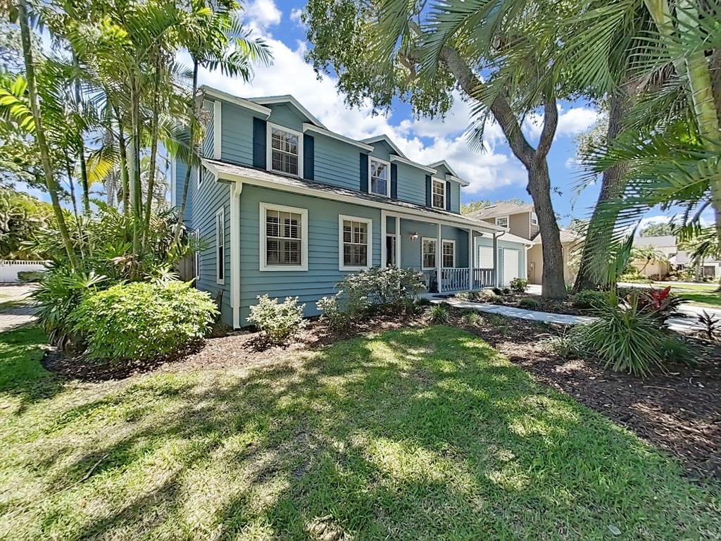 A two-story blue house with a front porch and dormer windows sits on a lawn — 7645 HARBOR VIEW WAY, SEMINOLE, FL