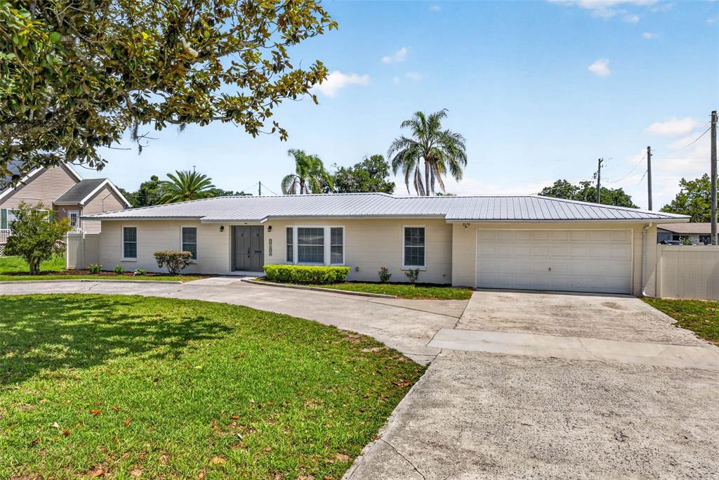A single-story house with a light-colored exterior, a metal roof, and an attached garage — 37121 MERIDIAN AVENUE, DADE CITY, FL