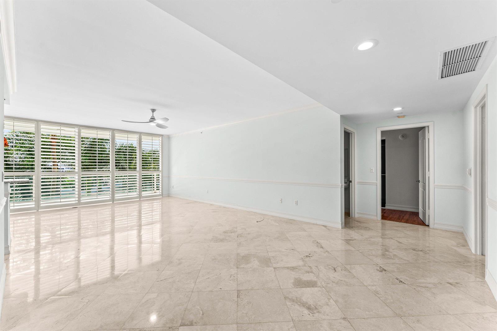 An empty room with light-colored tile flooring, white walls, and floor-to-ceiling plantation shutters — 550 SE Mizner Boulevard # B501, Boca Raton FL 33432, BOCA RATON, FL