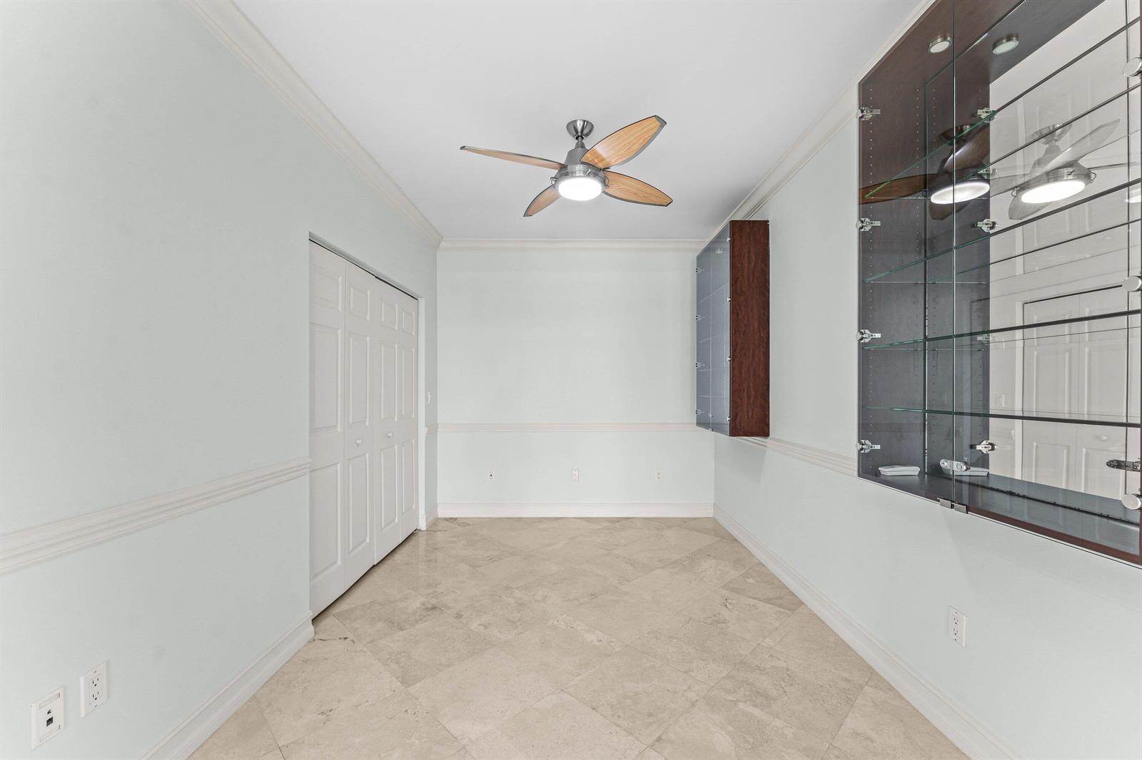 A room with light-colored tile flooring, a ceiling fan, a closet, and built-in glass shelving — 550 SE Mizner Boulevard # B501, Boca Raton FL 33432, BOCA RATON, FL