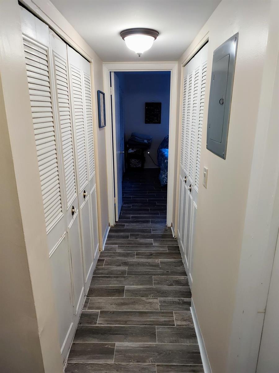 A hallway with wood-look tile flooring, louvered closet doors, and an electrical panel — 2302 Sunrise Boulevard # 104, Fort Pierce FL 34982, FORT PIERCE, FL