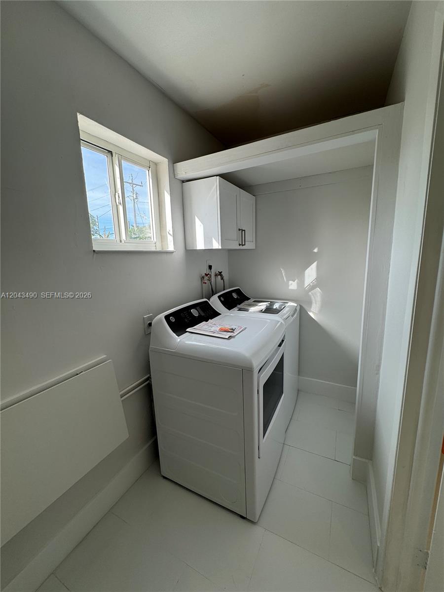 A laundry room features white appliances, white cabinetry, and a window against white walls — 951 E 32nd St, Hialeah FL 33013, HIALEAH, FL