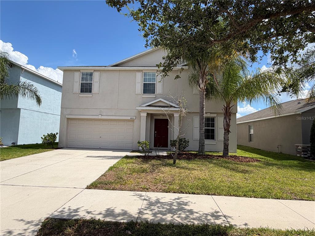 A two-story beige house with a two-car garage and a front yard with palm trees — 10013 CRESTED FRINGE DRIVE, RIVERVIEW, FL