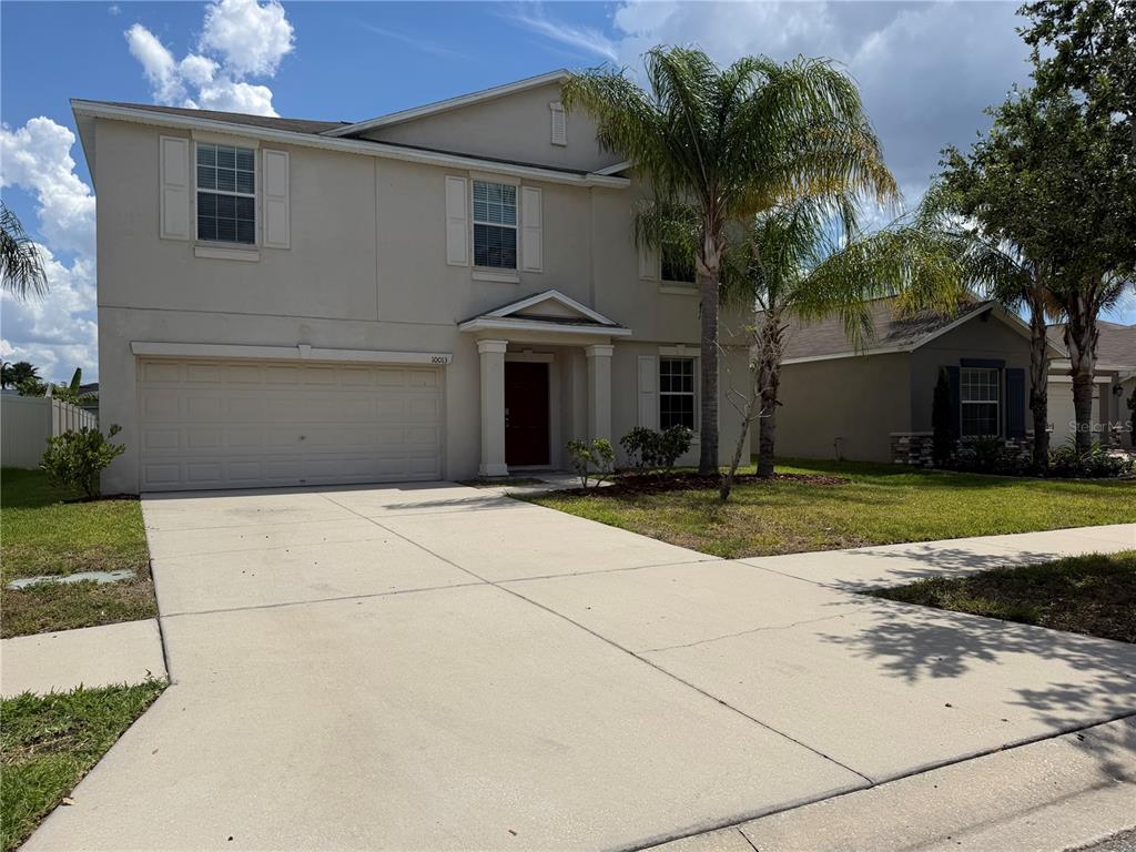A two-story beige house with a two-car garage and a palm tree in the yard — 10013 CRESTED FRINGE DRIVE, RIVERVIEW, FL