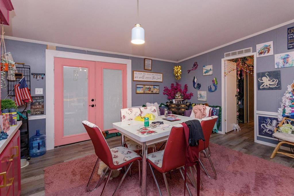 A dining room features a white table, red chairs, a pink rug, and pink double doors — 106 LEISURE WORLD DRIVE N, DEBARY, FL