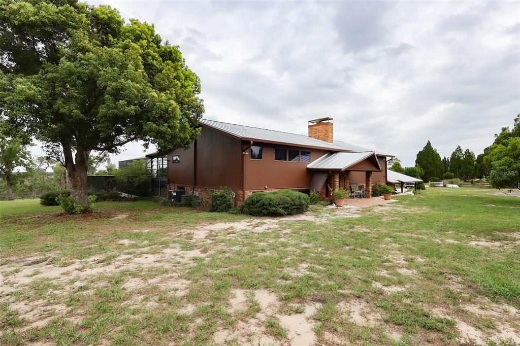 A brown house with a metal roof and an attached carport sits on a lawn — 5757 TRASK ROAD, FORT MEADE, FL