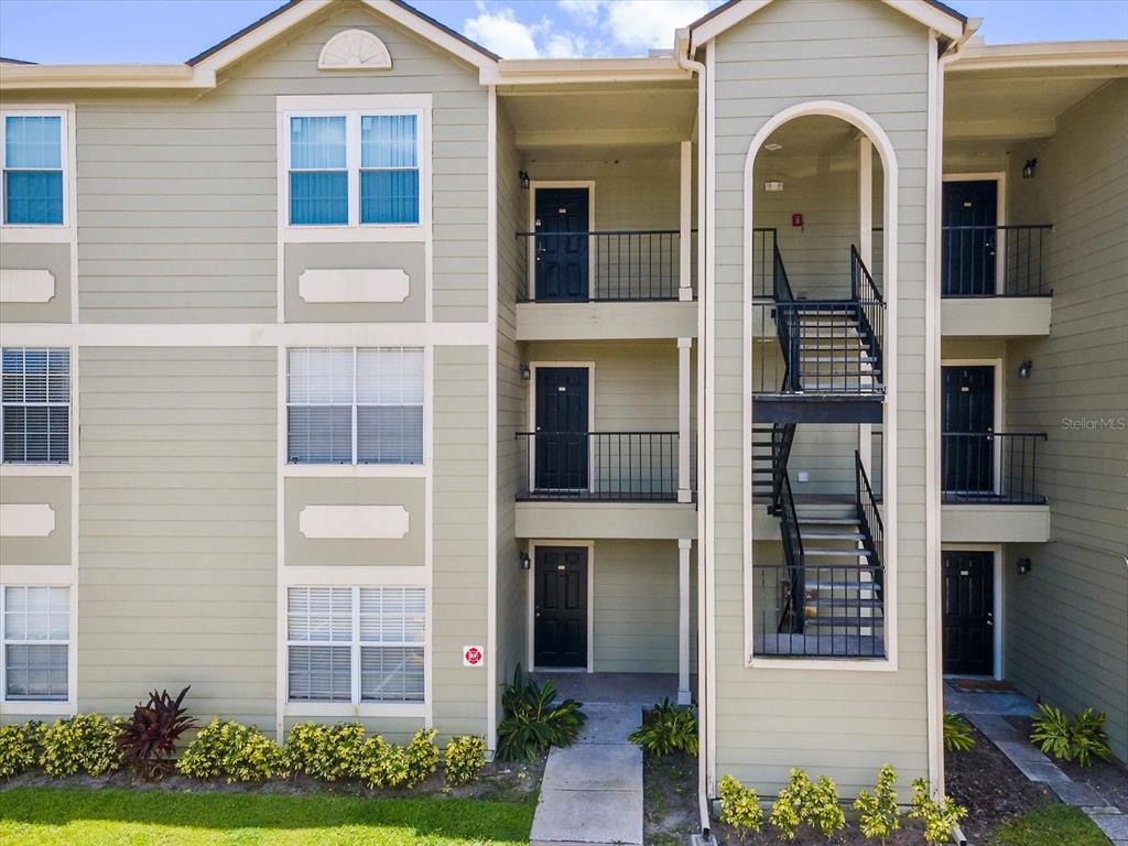 An exterior view of a three-story apartment building with stairs and balconies — 2550 N ALAFAYA TRAIL UNIT 9201, ORLANDO, FL