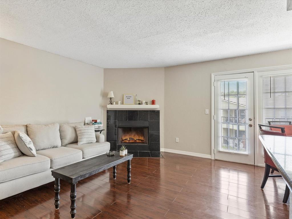 A living room features a black tile fireplace, hardwood floors, and a glass door — 2550 N ALAFAYA TRAIL UNIT 9201, ORLANDO, FL