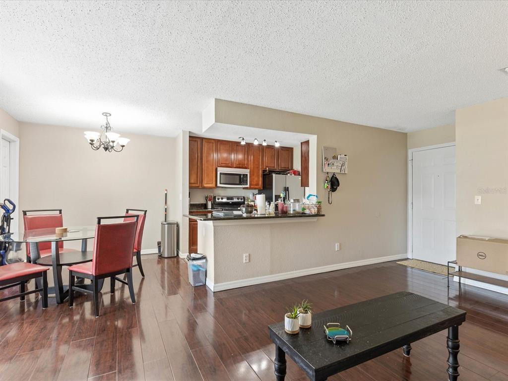 A dining area and kitchen with dark wood cabinets, granite countertops, and hardwood flooring — 2550 N ALAFAYA TRAIL UNIT 9201, ORLANDO, FL