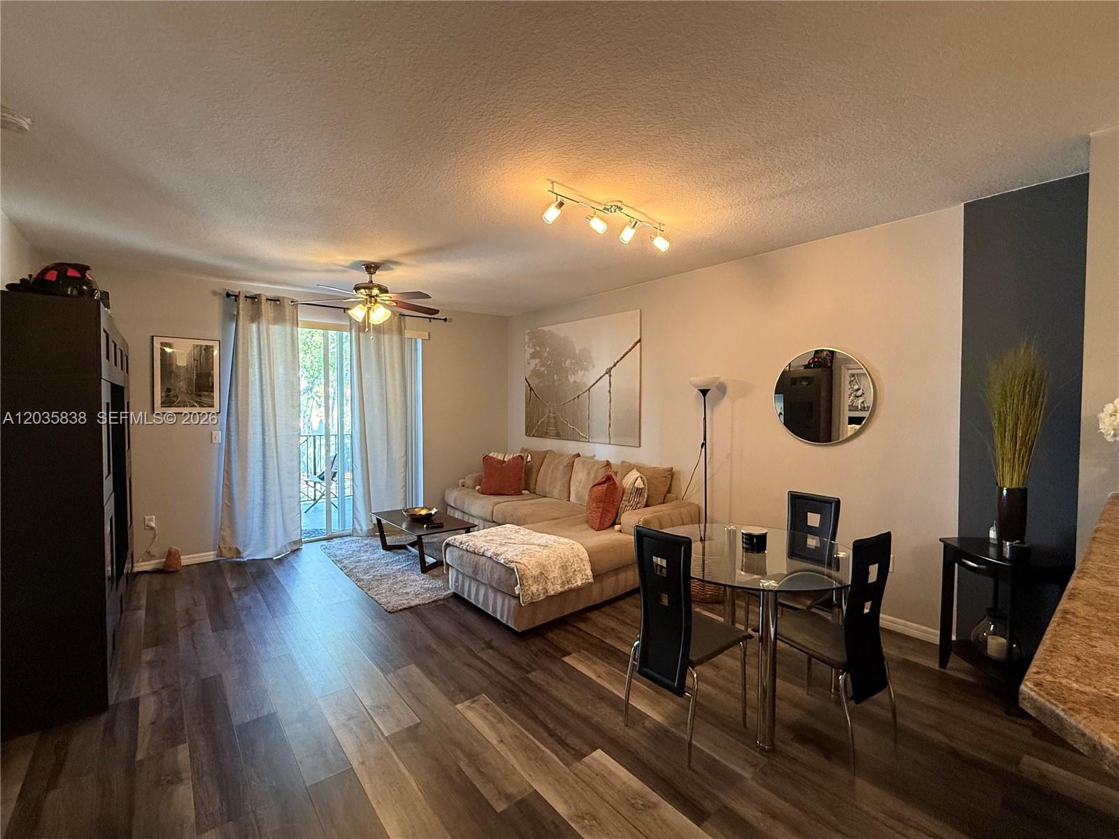 This living and dining room features wood-look flooring, a sectional sofa, and a glass table — 250 NE 3rd Ave # 1210, Delray Beach FL 33444, DELRAY BEACH, FL