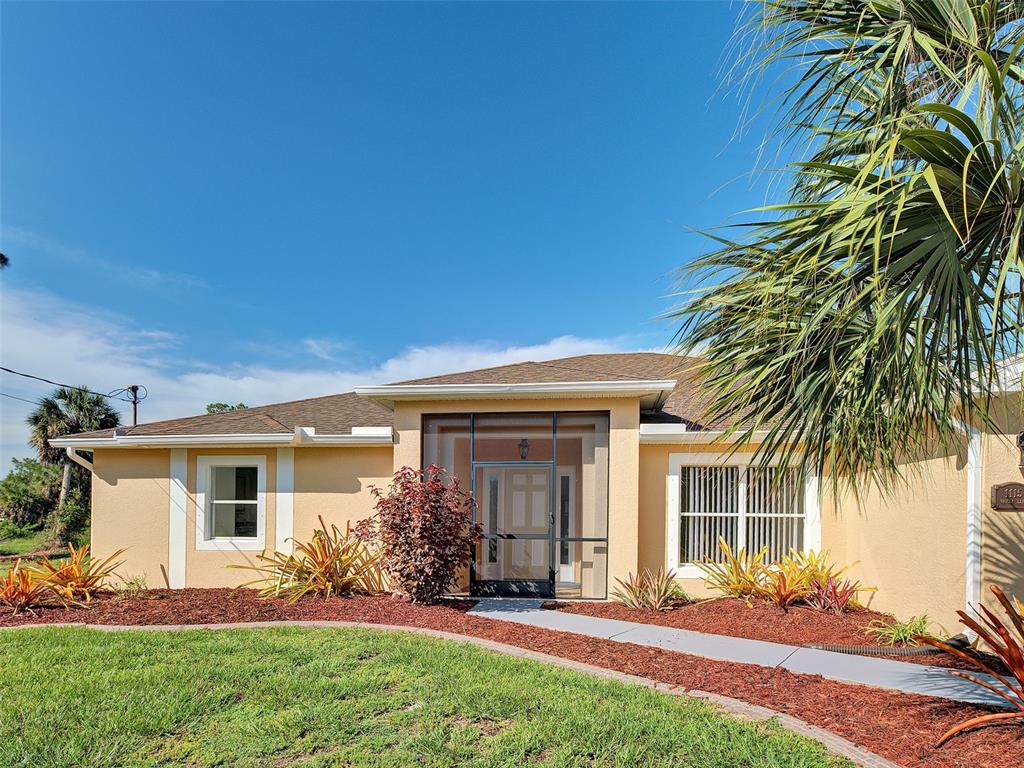 A single-story house with a tan stucco exterior, a screened front entryway, and a palm tree — 1115 URMEY LANE, NORTH PORT, FL