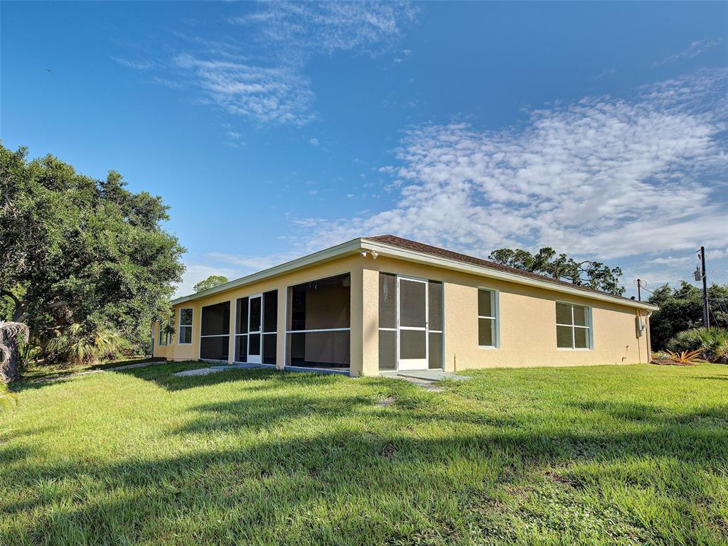 A single-story house with a screened-in porch and tan stucco exterior sits on a lawn — 1115 URMEY LANE, NORTH PORT, FL