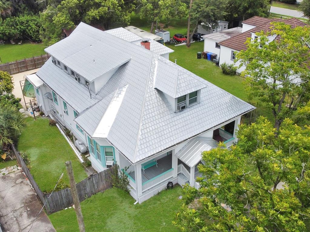 A white two-story house with a front porch and a metal roof stands on a lawn — 501 SUMNER STREET, KISSIMMEE, FL