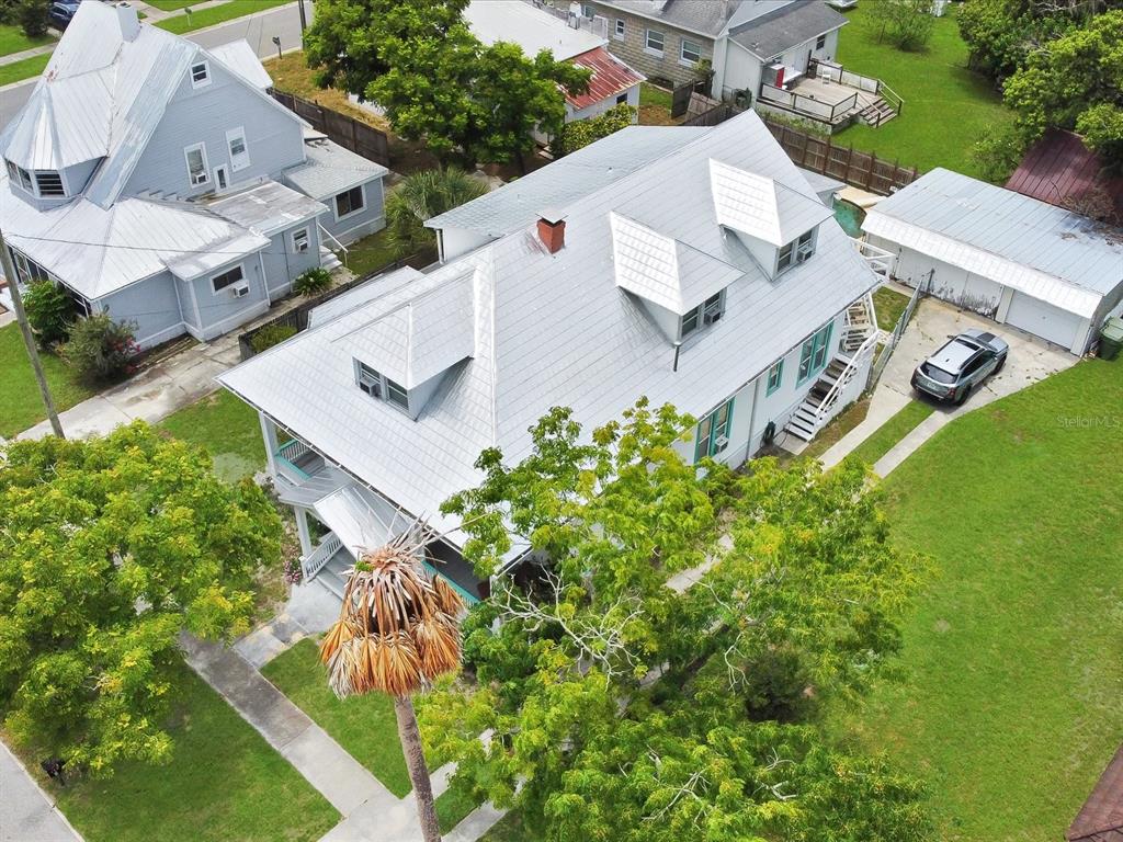 A covered front porch features white siding, a glass storm door, and potted plants — 501 SUMNER STREET, KISSIMMEE, FL